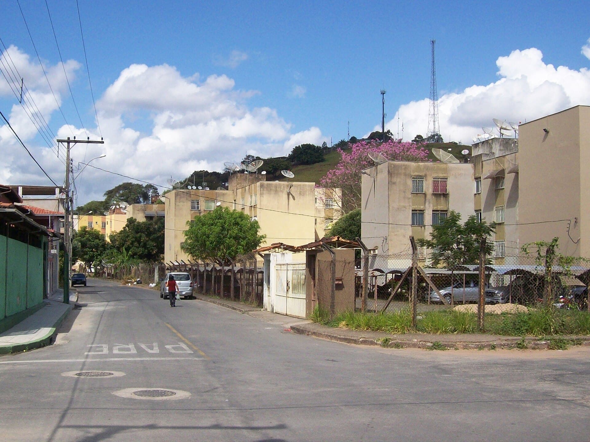 Rua de bairro residencial com casas e prédios baixos no bairro Floresta, em Coronel Fabriciano (MG).