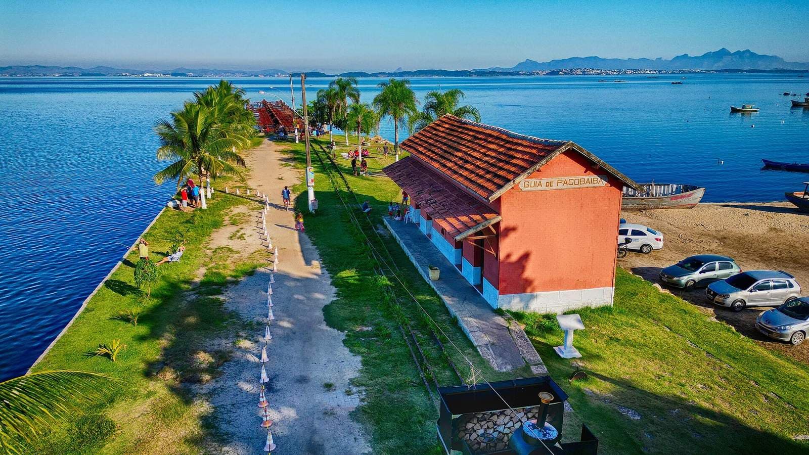 Vista aérea da estação Guia de Pacobaíba, à beira da Baía de Guanabara, em Magé (RJ), com moradores à beira d'água.