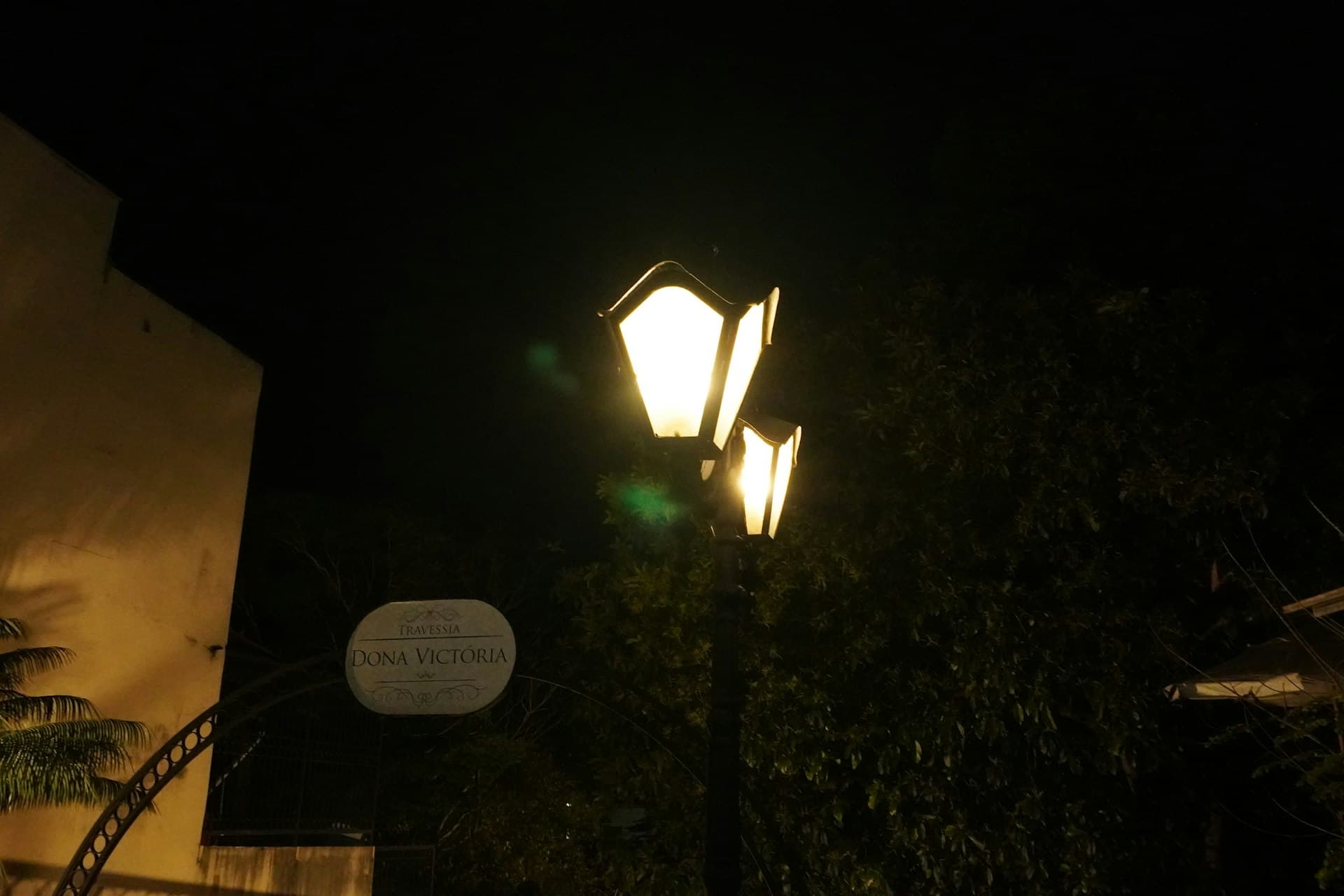 Postes de luz iluminando rua urbana brasileira à noite com céu escuro